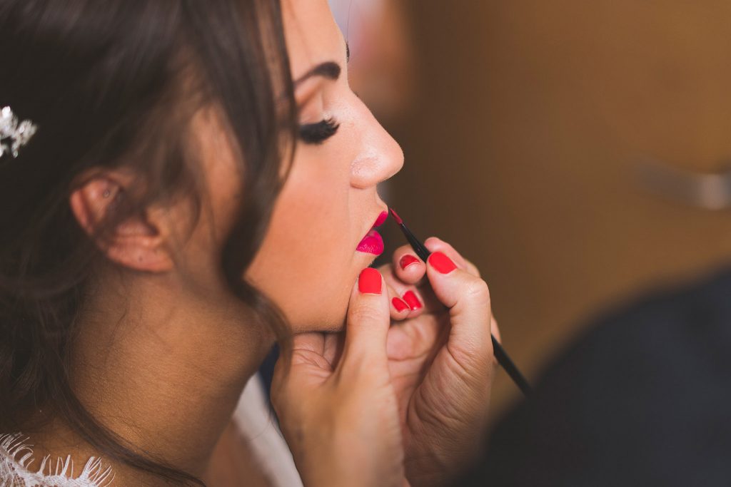 La maquilladora Lorena Fernández retocando los labios rojos de la novia.